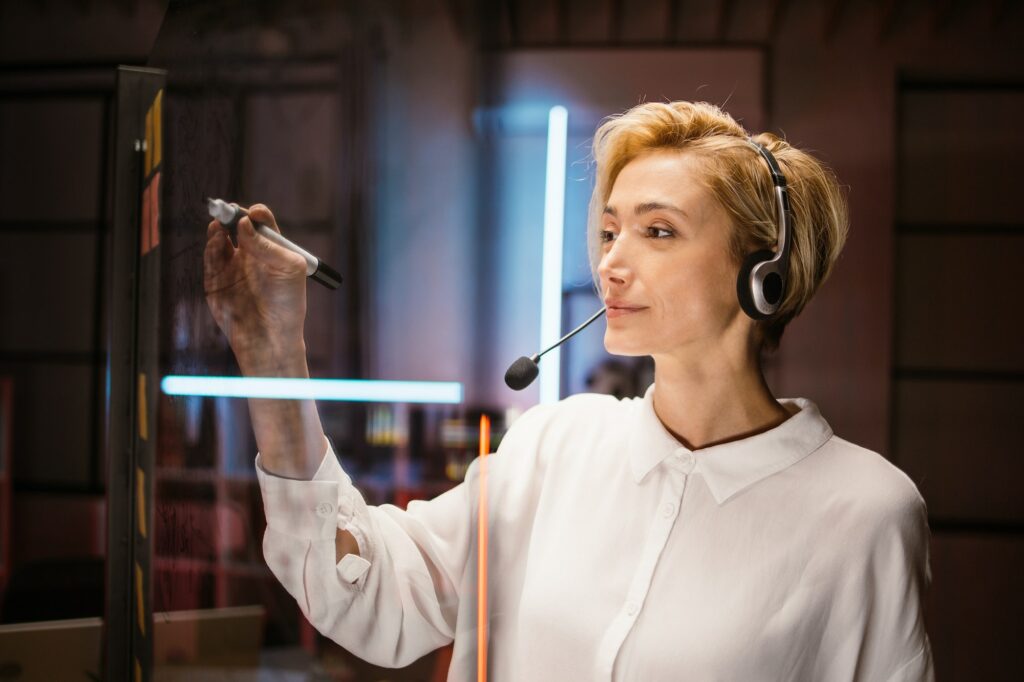 Caucasian female employee, managing working tasks, writing notes on glass transparent wall in office