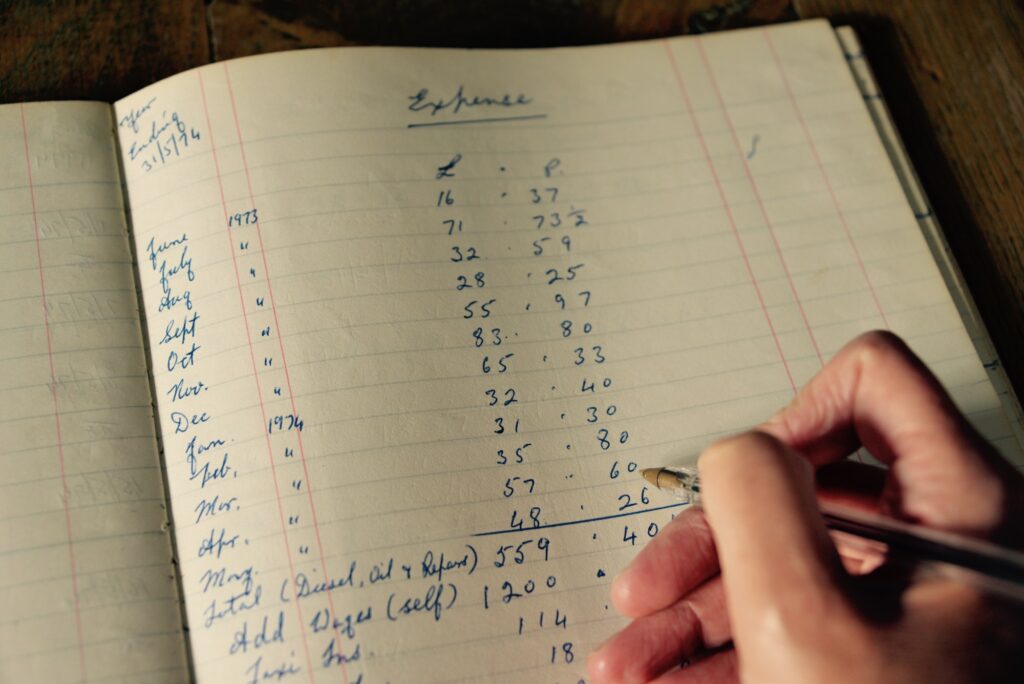 a hand holding a pen writing in an accounting book